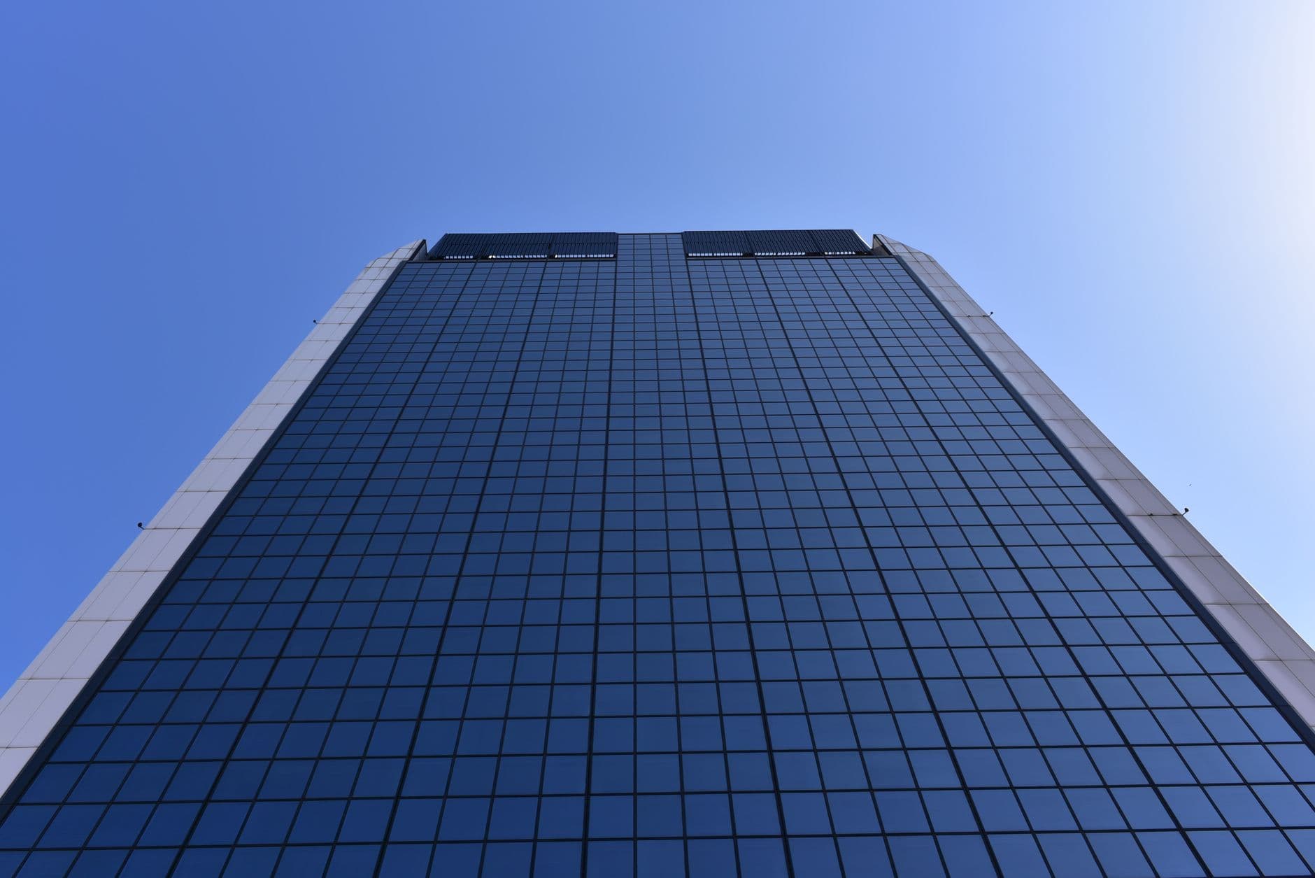 Commercial glass tower exterior Glass commercial high-rise tower against a clear blue sky